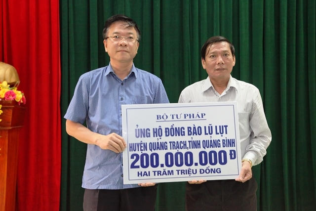 Bộ trưởng Bộ tư pháp Lê Thành Long trao quà cho đại diện nhân dân huyện Quảng Trạch, tỉnh Quảng Bình.