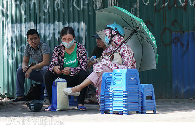Việc thời tiết nắng nóng khiến cho khá nhiều phụ huynh tỏ ra mệt mỏi trong lúc chờ con em mình đi thi. Họ phải dùng ô, đeo khẩu trang kín mít để tránh nắng nóng.