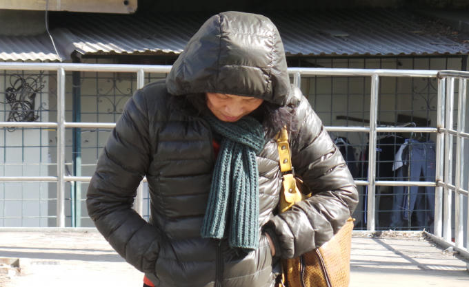 M&ocirc;̣t người phụ nữ cho tay vào túi áo cho &acirc;́m mặc dù trời Hà N&ocirc;̣i đang có nắng.