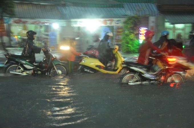 Dòng người dắt xe lội nước để về nhà sau giờ tan việc.