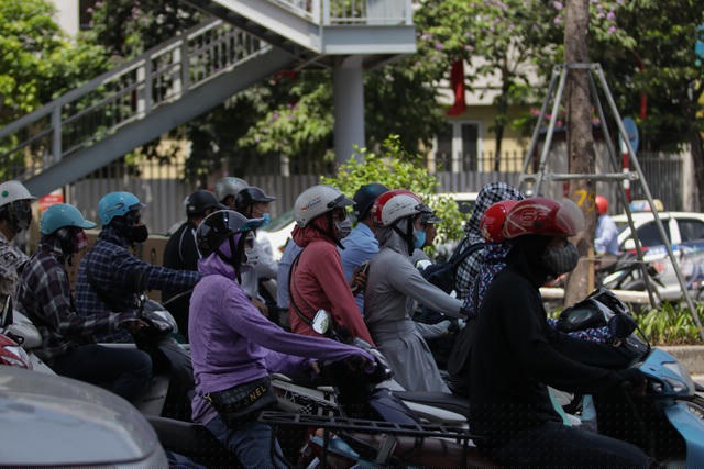 Người tham gia giao thông dừng đèn đỏ cách xa hàng chục mét để tận dụng bóng mát của cầu vượt trên đường.
