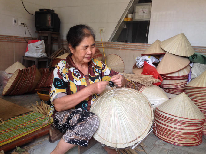 Bà Hoàng Thị Sáng say mê luồn từng sợi chỉ để nhanh hoàn thiện chiếc nón trong ngày