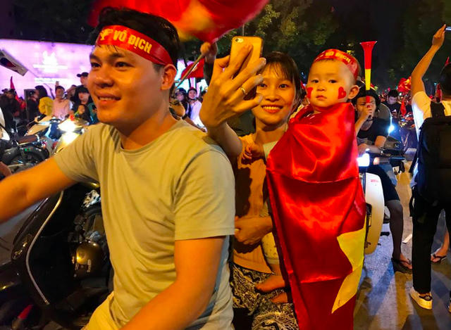 Em bé được bố mẹ choàng lên người lá cờ đỏ sao vàng để ăn mừng chiến thắng