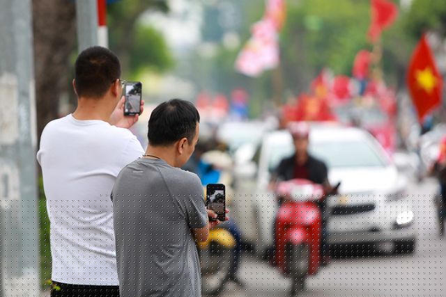 Người dân hai bên đường ghi lại hình ảnh của đoàn cổ động viên đang diễu hành.