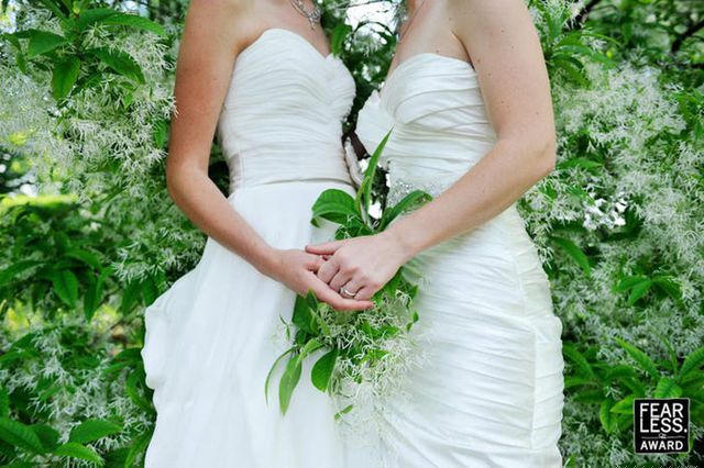 Năm 2013, Karen Evans chụp bức ảnh hai cô dâu đang nắm chặt tay nhau, phía sau họ là phông xanh của lá và hoa.