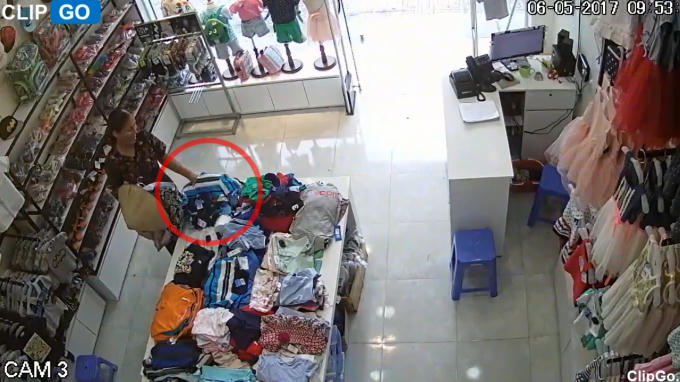 Hình ảnh người phụ nữ lấy trộm đồ trong shop quần áo.