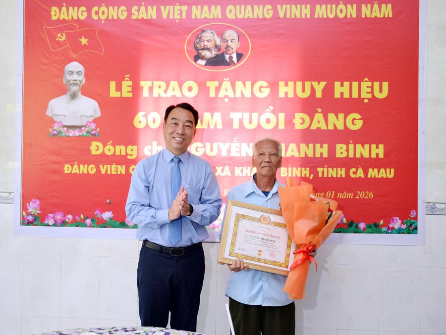 Ông Lữ Quang Ngời trao Huy hiệu 60 năm tuổi Đảng và tặng hoa chúc mừng đảng viên Nguyễn Thanh Bình.