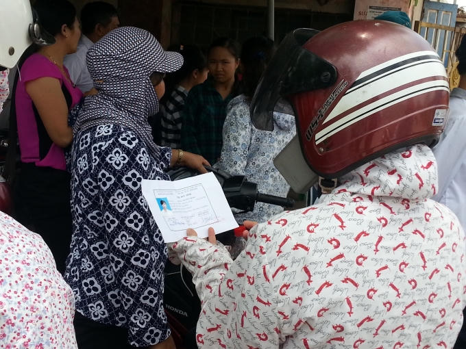 Phụ huynh đang xem lại thông tin trên thẻ dự thi cho con mình.