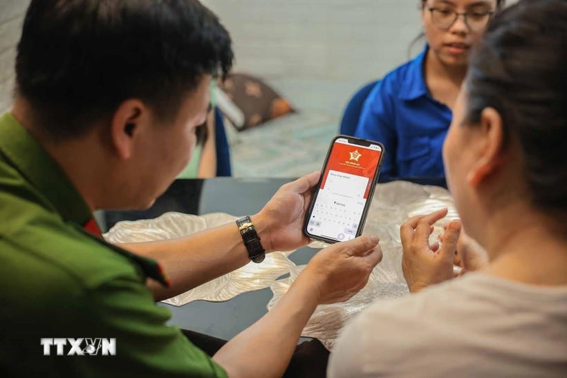 Tổ chuyển đổi số cộng đồng hướng dẫn người dân sử dụng ứng dụng VNeID. Ảnh: TTXVN