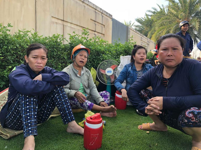 Các công nhân ngồi thẫn thờ sau vụ cháy.