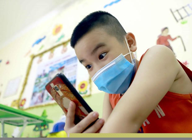 Một học sinh thích thú khi được gọi điện thoại có hình từ khu cách ly với bà nội. (Ảnh: Hoàng Hùng/TTXVN)