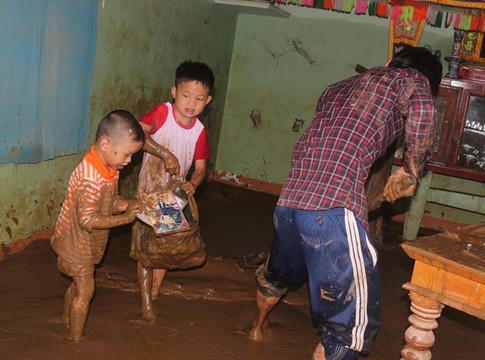 Học sinh ở H.Ho&agrave;i &Acirc;n, B&igrave;nh Định thu dọn cặp s&aacute;ch trong đống b&ugrave;n non sau cơn lũ. ảnh Lưu Quốc Tr&iacute;