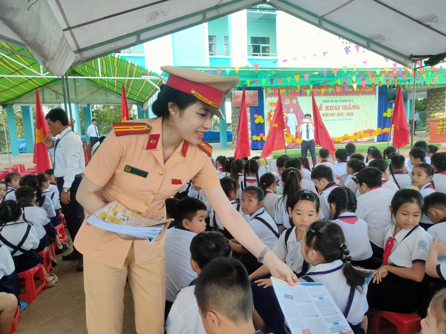 Cảnh sát giao thông phát tờ rơi tuyên truyền, hướng dẫn kỹ năng tham gia giao thông an toàn cho học sinh.