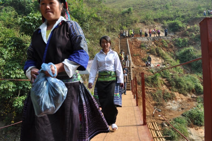 Dân làng phấn khởi đi lại qua cây cầu mới.