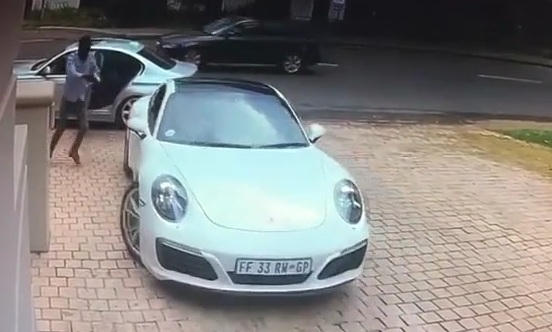 T&ecirc;n cướp xuống xe, chạy tới, cầm s&uacute;ng chĩa v&agrave;o l&aacute;i xe Porsche.