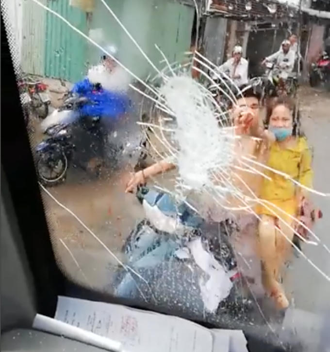 Cửa kính xe ô tô bị đập vỡ, trên kính xe còn có vết máu của nam thanh niên đi xe máy do đấm mạnh vào cửa kính.