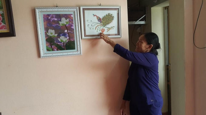 Bà Thơm chỉ những bức tranh của con gái mình làm ra.