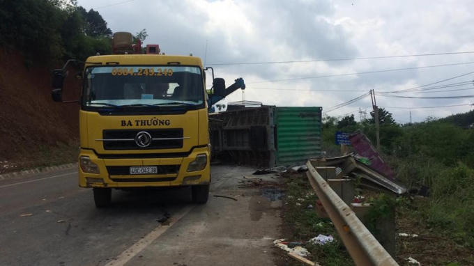 Thùng container lật nghiêng xuống đường.
