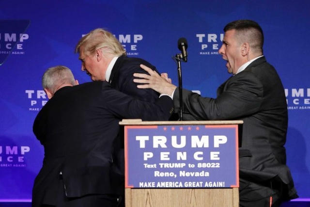 Mật vụ hộ tống ông Trump khỏi sân khấu. (Ảnh: Reuters)