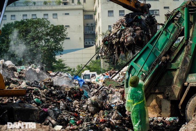 Công nhân vệ sinh thuộc Công ty môi trường đô thị Vĩnh Yên đang tiến hành dọn rác ra khỏi bãi tập kết rác tạm thời trên phố Phạm Văn Bạch.