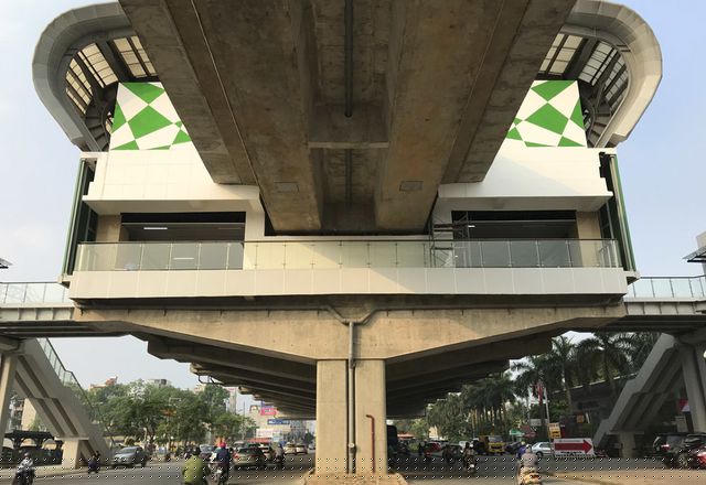 Ga Yên Nghĩa nhìn từ tim đường. Hiện vẫn chưa hoàn thiện xong hạng mục kiến trúc các nhà ga và các đơn thể khu Depot; mái che thang cuốn các nhà ga; đấu nối thoát nước khu gian ga vành đai 3, cảnh quan, cây xanh... trong khu Depot; điện, thẻ vé và hoàn thiện các thủ tục để đánh giá chứng nhận an toàn hệ thống, nghiệm thu và bàn giao dự án.