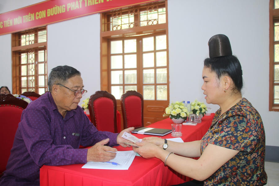 Ông Tòng Văn Thẳm, Chi hội trưởng Hội người cao tuổi bản Pàn, xã Mường Bú đang nhận tiền hỗ trợ.