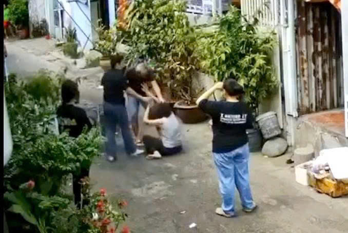 Trong khi nạn nhân bị hành hung, những người có mặt không những không can ngăn mà còn thản nhiên dùng điện thoại quay, chụp. (ảnh cắt từ clip do đương sự cung cấp).
