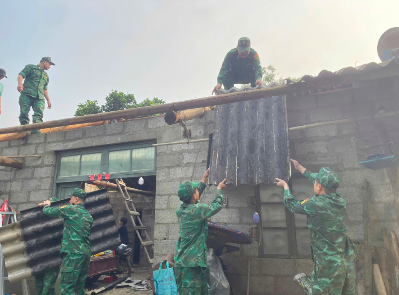 Cán bộ, chiến sĩ đồn Biên phòng Cửa khẩu quốc tế Tà Lùng giúp gia đình Nguyễn Văn Hoàng khắc phục hậu quả do lốc xoáy gây ra. Ảnh Báo Cao Bằng