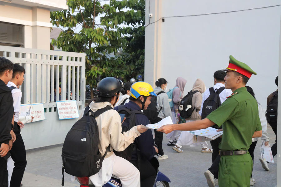 Lực lượng công an phát tờ rơi tuyên truyền trước cổng trường