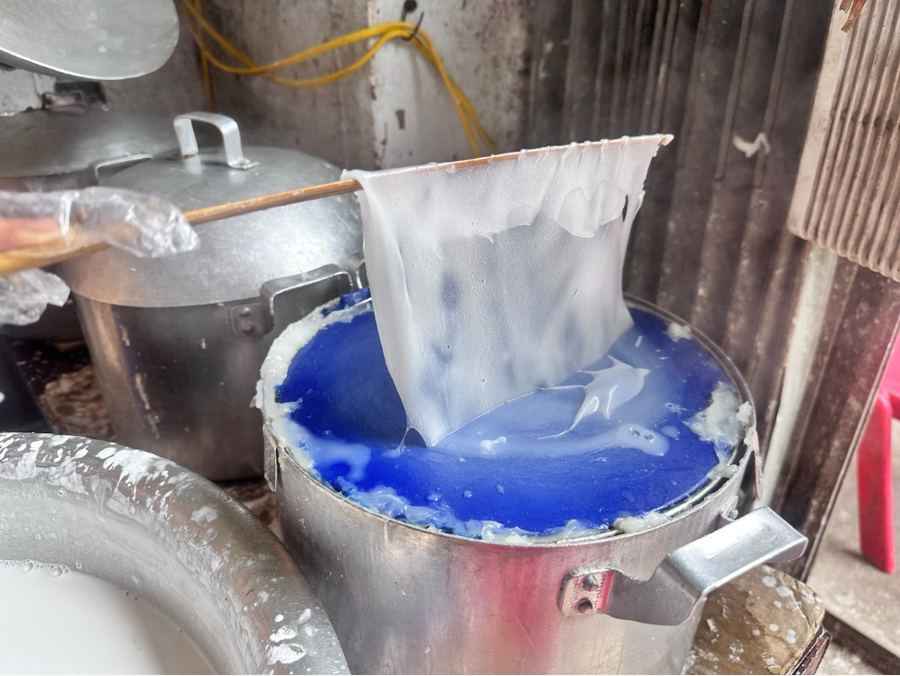 Người thợ dùng đũa tre khéo léo nhấc lớp bánh mỏng tang.