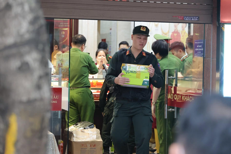 Lực lượng chức năng mang các thùng tài liệu ra khỏi cửa hàng vàng Bảo Tín Minh Châu hôm 25/3.