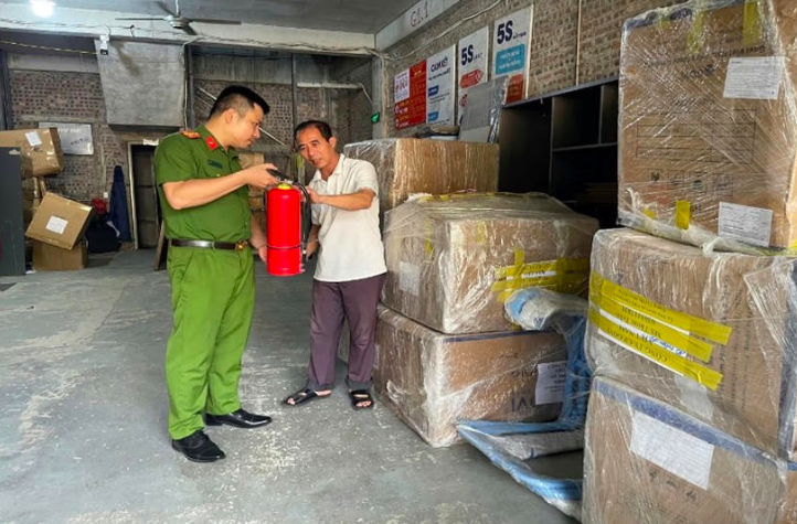 Lực lượng công an hướng dẫn người đứng đầu cơ sở sử dụng trang thiết bị chữa cháy ban đầu. (Ảnh: Công an Hà Nội).