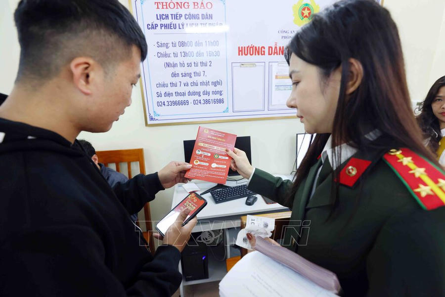 Cán bộ, chiến sĩ Phòng Hồ sơ nghiệp vụ, Công an TP Hà Nội hướng dẫn người dân làm thủ tục cấp Phiếu lý lịch tư pháp. (Ảnh: Phạm Kiên - TTXVN)