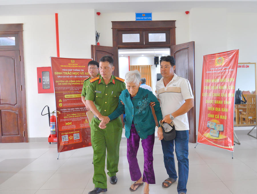 Cán bộ Công an hỗ trợ thân nhân liệt sĩ cao tuổi đến điểm thu nhận mẫu ADN.