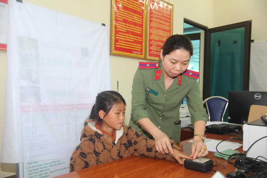 Cán bộ Công an xã Tùng Vài tận tình hướng dẫn các bước thực hiện định danh mức độ 2 cho trẻ em 6- 12 tuổi. (Ảnh: Hoàng Chính).