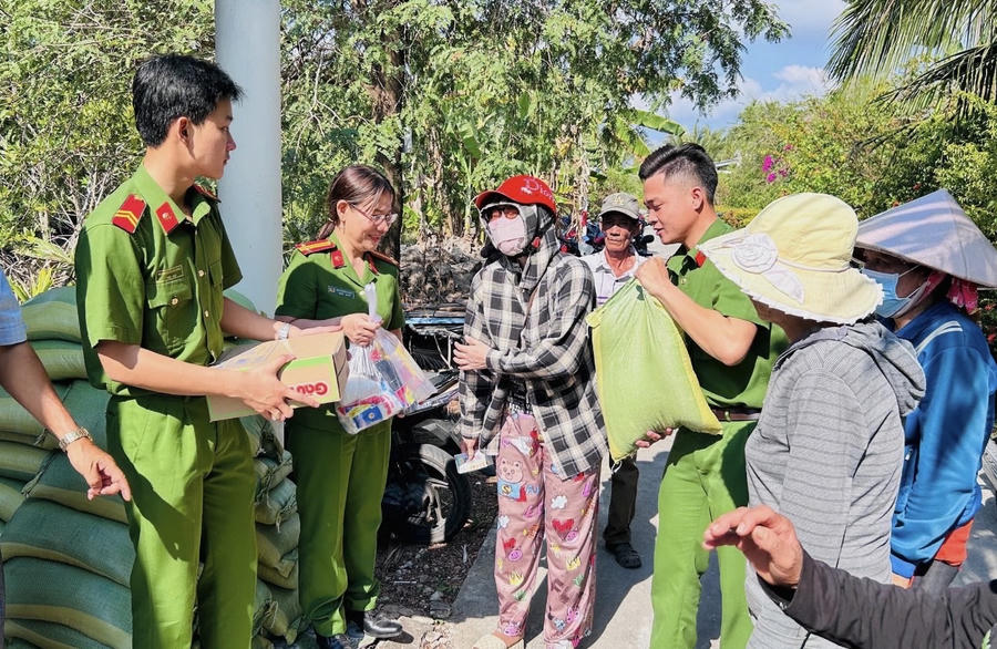 Cán bộ Phòng Cảnh sát thi hành án hình sự và hỗ trợ tư pháp Công an Cà Mau, trao quà cho người dân tại ấp Tân Tiến, xã Trần Văn Thời.