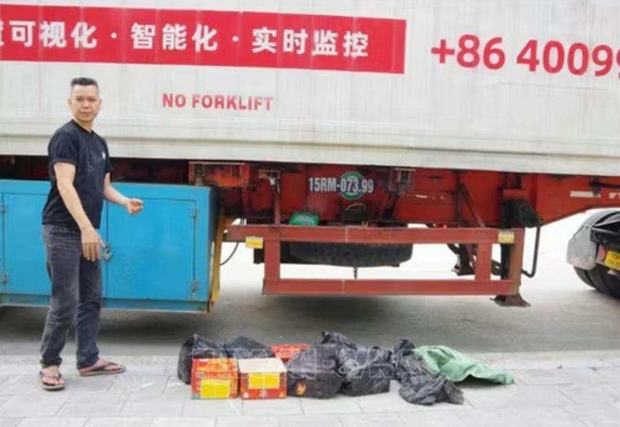 Đồng Văn Bốn cùng số pháo nổ được cất giấu dưới gầm rơmoóc tại cửa khẩu quốc tế Hữu Nghị. Ảnh: TTXVN.