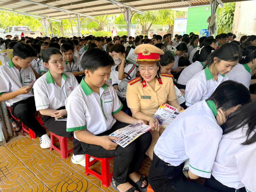 Thiếu tá Trịnh Ngọc Thảo phát tờ rơi tuyên truyền, giải đáp các tình huống giao thông thực tế và giao lưu với học sinh Trường THCS - THPT Khánh An (tỉnh Cà Mau). 