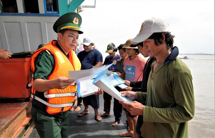 Cán bộ đồn Biên phòng Tây Yên, Ban chỉ huy Bộ đội Biên phòng tỉnh An Giang phát tờ rơi, tuyên truyền chống khai thác IUU cho ngư dân.