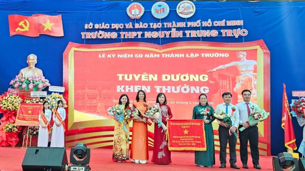 Bà Hoàng Thị Kim Thu - Bí thư Đảng ủy, Chủ tịch HĐND phường An Hội Đông (thứ 3 bên phải qua) trao Cờ Đơn vị dẫn đầu phong trào thi đua của UBND TP HCM cho tập thể nhà trường