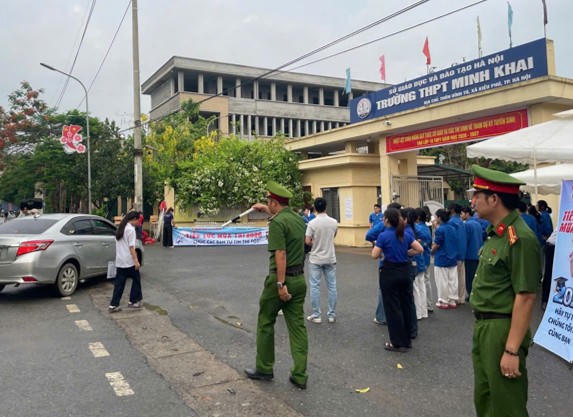 Lực lượng Công an xã Kiều Phú điều tiết, phân luồng các phương tiện giao thông ngoài cổng trường.
