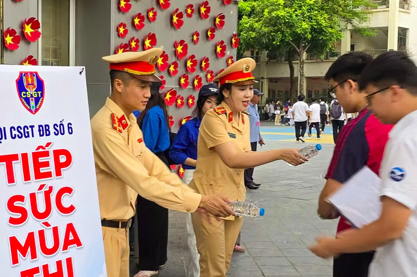 Đội CSGT đường bộ số 6 cùng Đoàn thanh niên phường Cầu Giấy hỗ trợ thí sinh sáng 11/6 tại điểm thi Trường THCS Dịch Vọng (Ảnh: Ngọc Tiến).