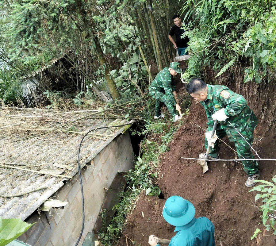 Cán bộ, chiến sĩ Đồn Biên phòng Cửa khẩu Săm Pun hỗ trợ người dân khắc phục hậu quả sạt lở đất. (Ảnh: Hà Linh)