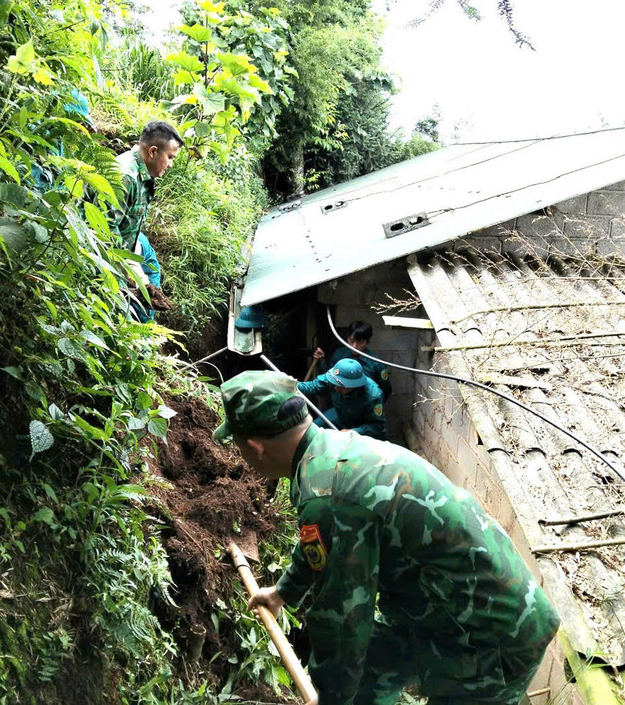 Cán bộ, chiến sĩ Đồn Biên phòng Cửa khẩu Săm Pun hỗ trợ người dân khắc phục hậu quả sạt lở đất. (Ảnh: Hà Linh)