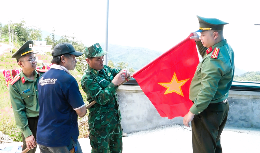 : Các lực lượng tặng cờ Tổ quốc cho nhân dân khu vực biên giới. (Ảnh: Hoàng Chính).