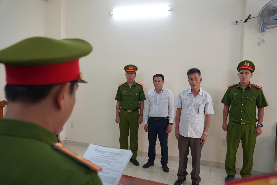 Cơ quan Cảnh sát điều tra Công an tỉnh tống đạt các quyết định đối với Trần Huỳnh Kiến Trúc (áo trắng) và Đỗ Ngọc Quang (áo ca rô). (Ảnh: Công an tỉnh Khánh Hòa)