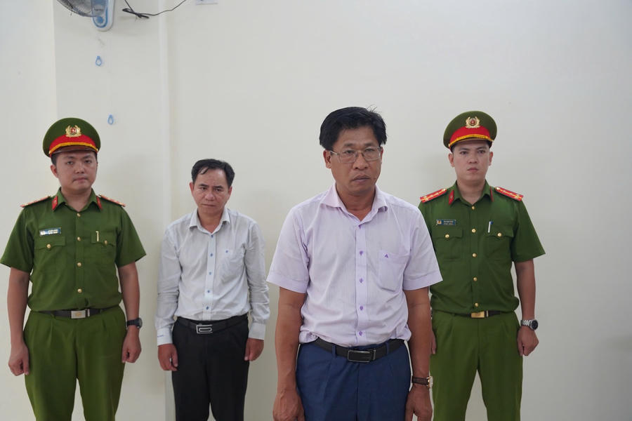 Bị can Hán Tấn Vĩnh An (áo trắng, đứng trước), Nguyễn Hữu Tân (áo trắng, đứng sau) đang nghe Cơ quan Cảnh sát điều tra Công an tỉnh Khánh Hòa tống đạt các quyết định liên quan. (Ảnh: Công an tỉnh Khánh Hòa)