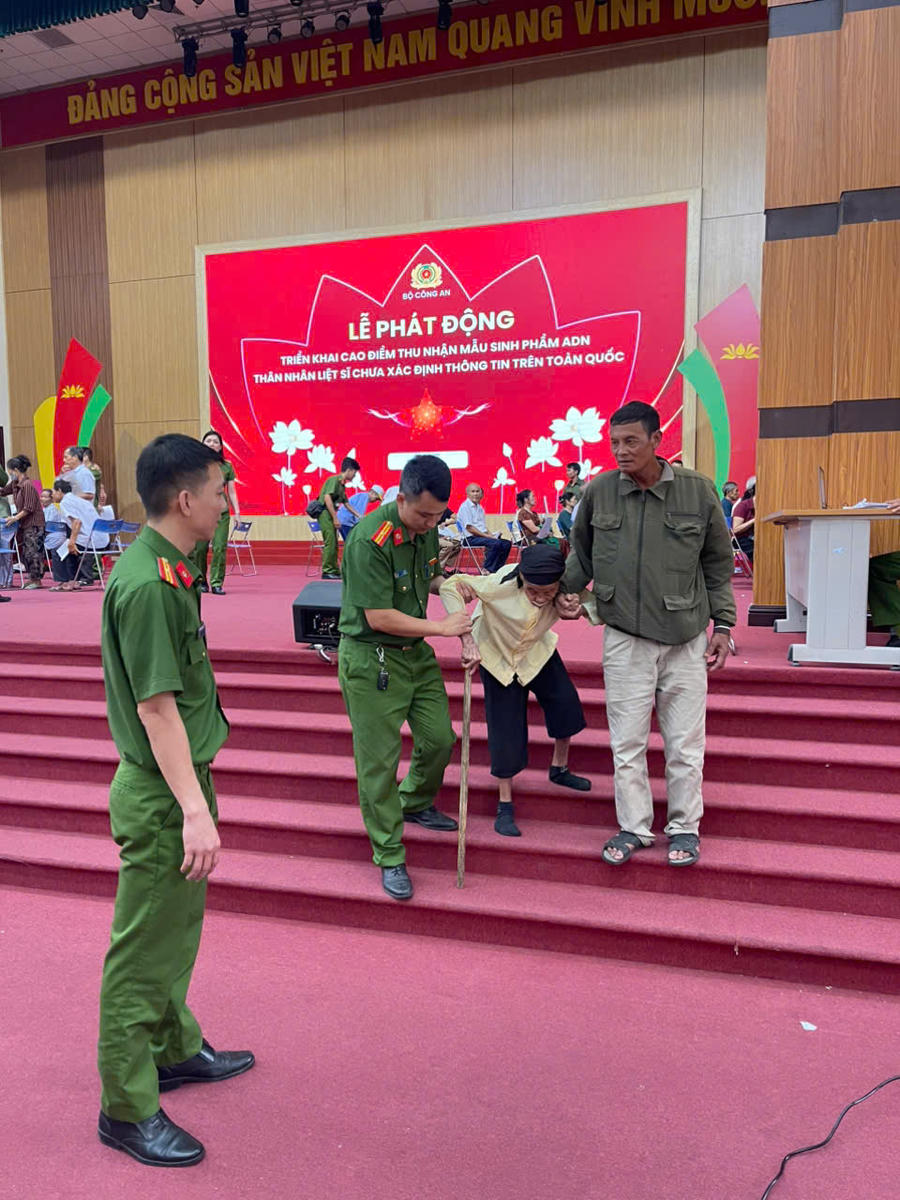Cán bộ, chiến sĩ Công an xã Vật Lại hỗ trợ thân nhân liệt sĩ cao tuổi di chuyển đến khu vực thu nhận mẫu ADN.