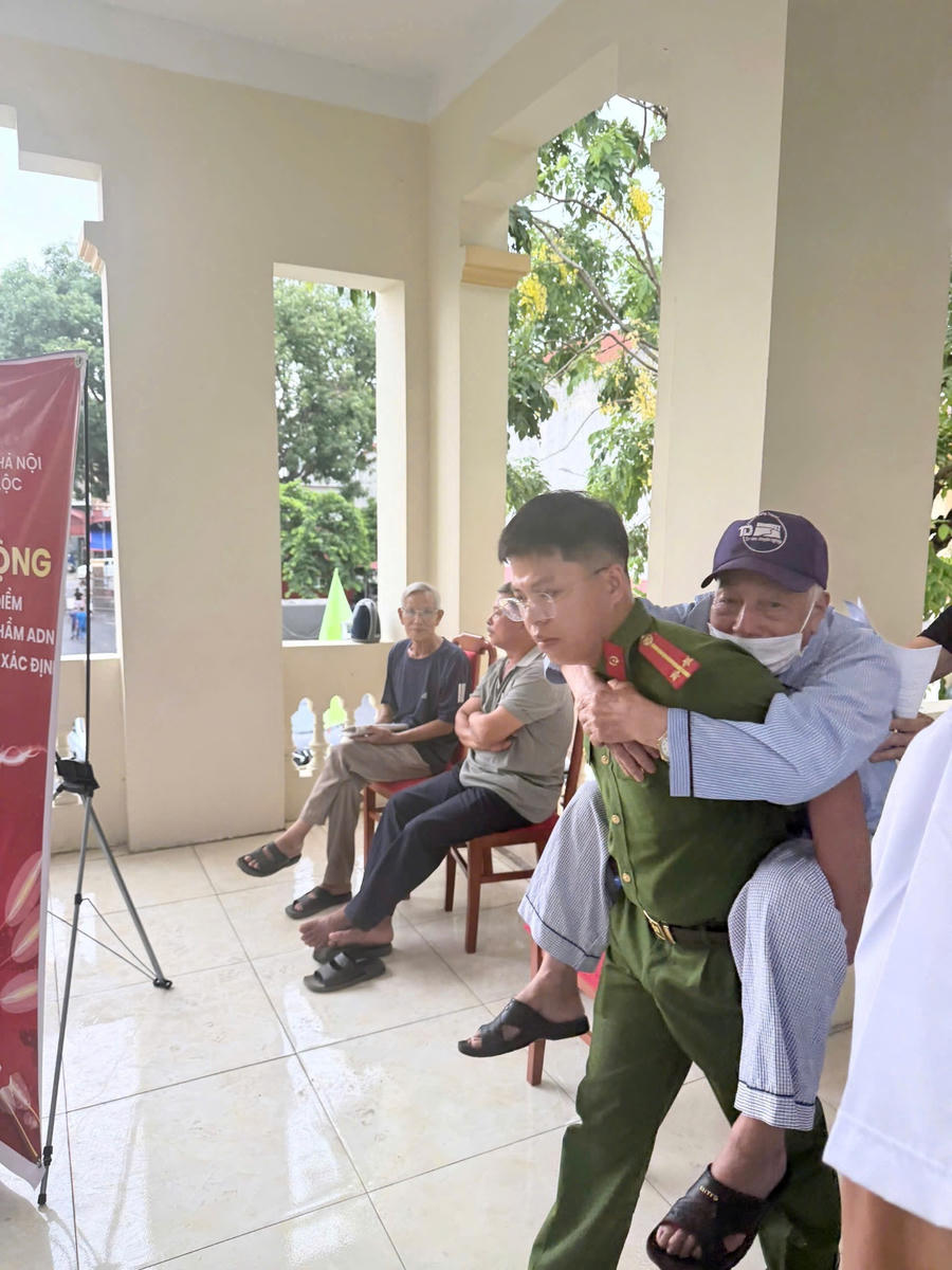 Cán bộ, chiến sĩ Công an xã Phúc Lộc hỗ trợ người cao tuổi tham gia thu nhận mẫu ADN.