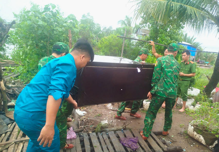 Cán bộ, chiến sĩ Đồn Biên phòng Đất Mũi hỗ trợ người dân di dời tài sản khỏi khu vực sạt lở.
